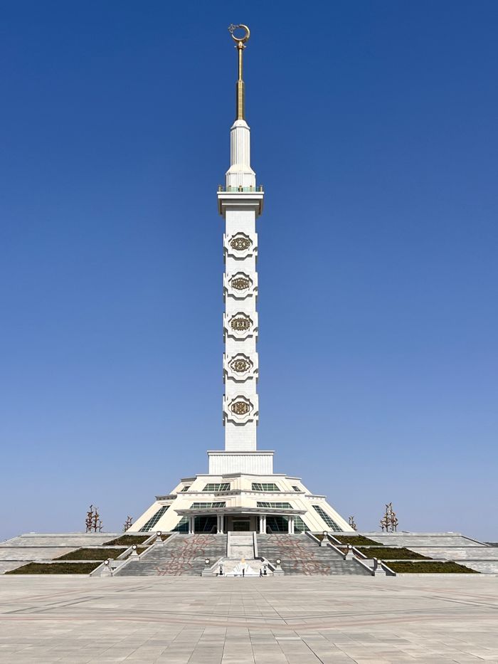 Tall marble monument under blue sky in Ashgabat, Turkmenistan, symbolizing neutrality.